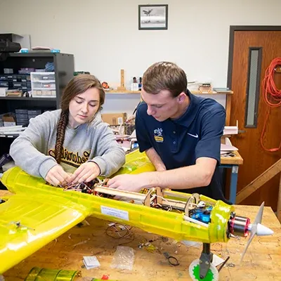 Students working on a large semi-transparent remote controlled electric propeller driven aircraft.