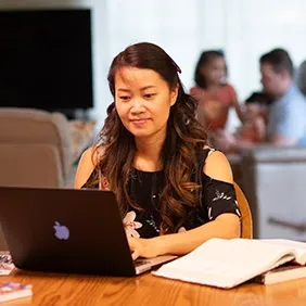 Female high school student sitting at table typing on computer