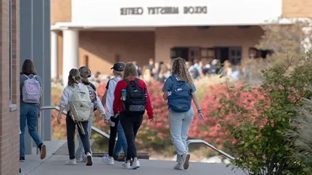 Group of college students with backpacks walking down sidewalk