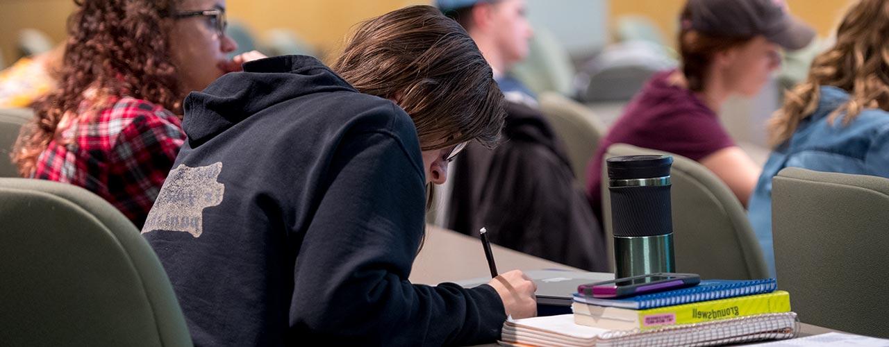 Female communication student taking notes in class