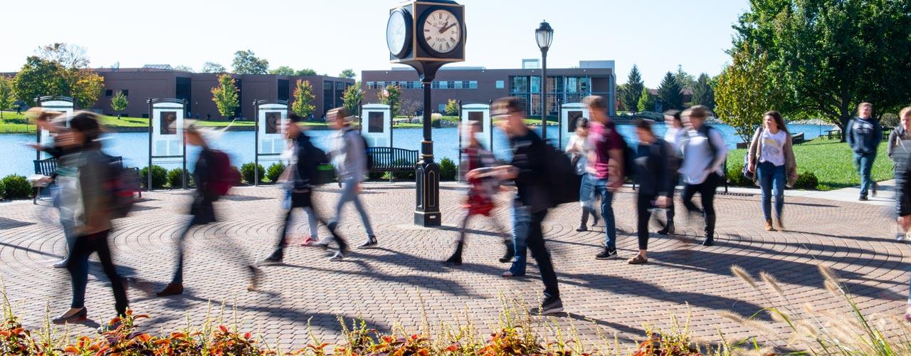 Rushing students walking by the clock outside of the SSC