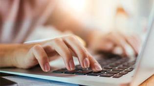 White male hands typing on a laptop