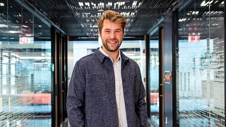 Man standing in a hallway smiling at the camera.